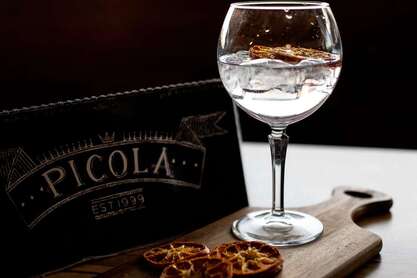 Picture of a fine glass of Gin & Tonic against our menu at Picola Italian